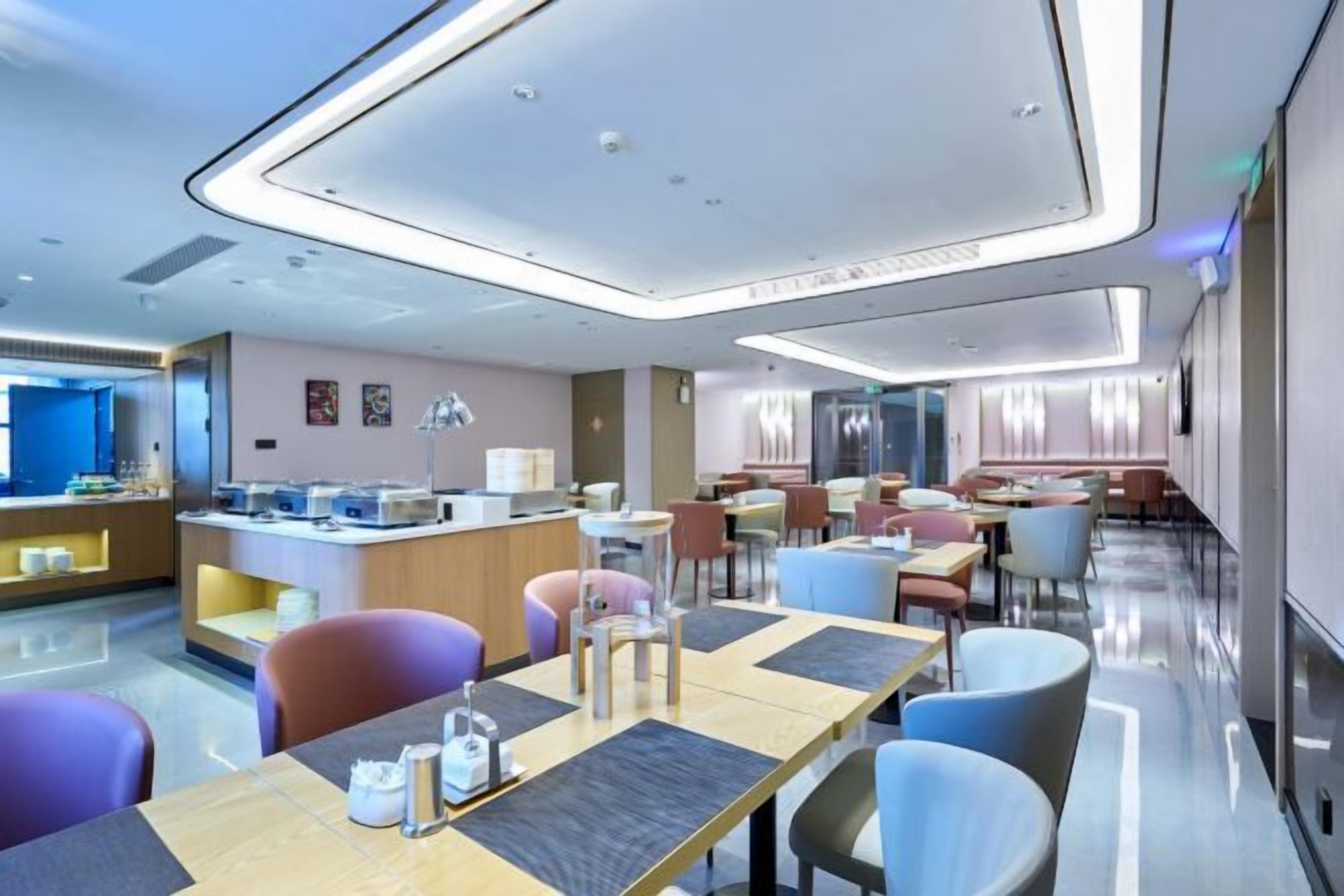 A modern hotel dining area with a central bar, multiple seating options, and a clean, contemporary design.