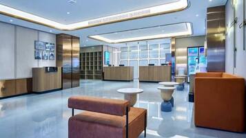 A modern lobby with a reception desk, seating areas, and a digital information kiosk.