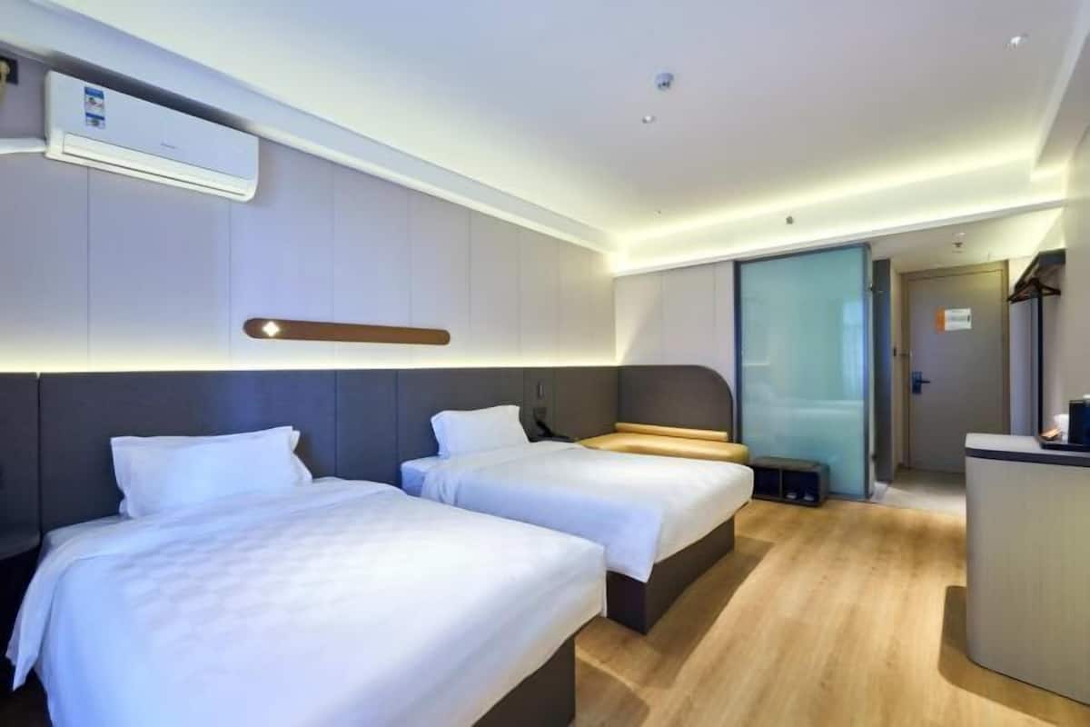 A hotel room with two beds, a desk, and a sliding door leading to a bathroom.