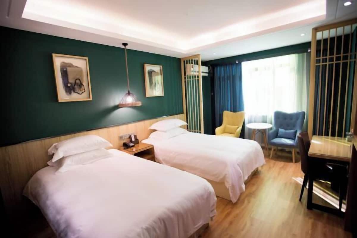 Ein Hotelzimmer mit zwei Betten, einem Schreibtisch, einem Stuhl und einem kleinen Tisch.