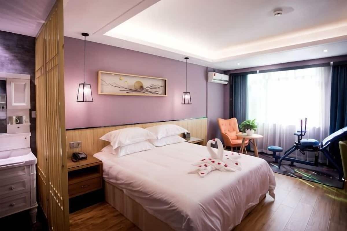 Ein Hotelzimmer mit einem Bett, Nachttischen, einem Sessel, einem Schreibtisch und einem Fenster.