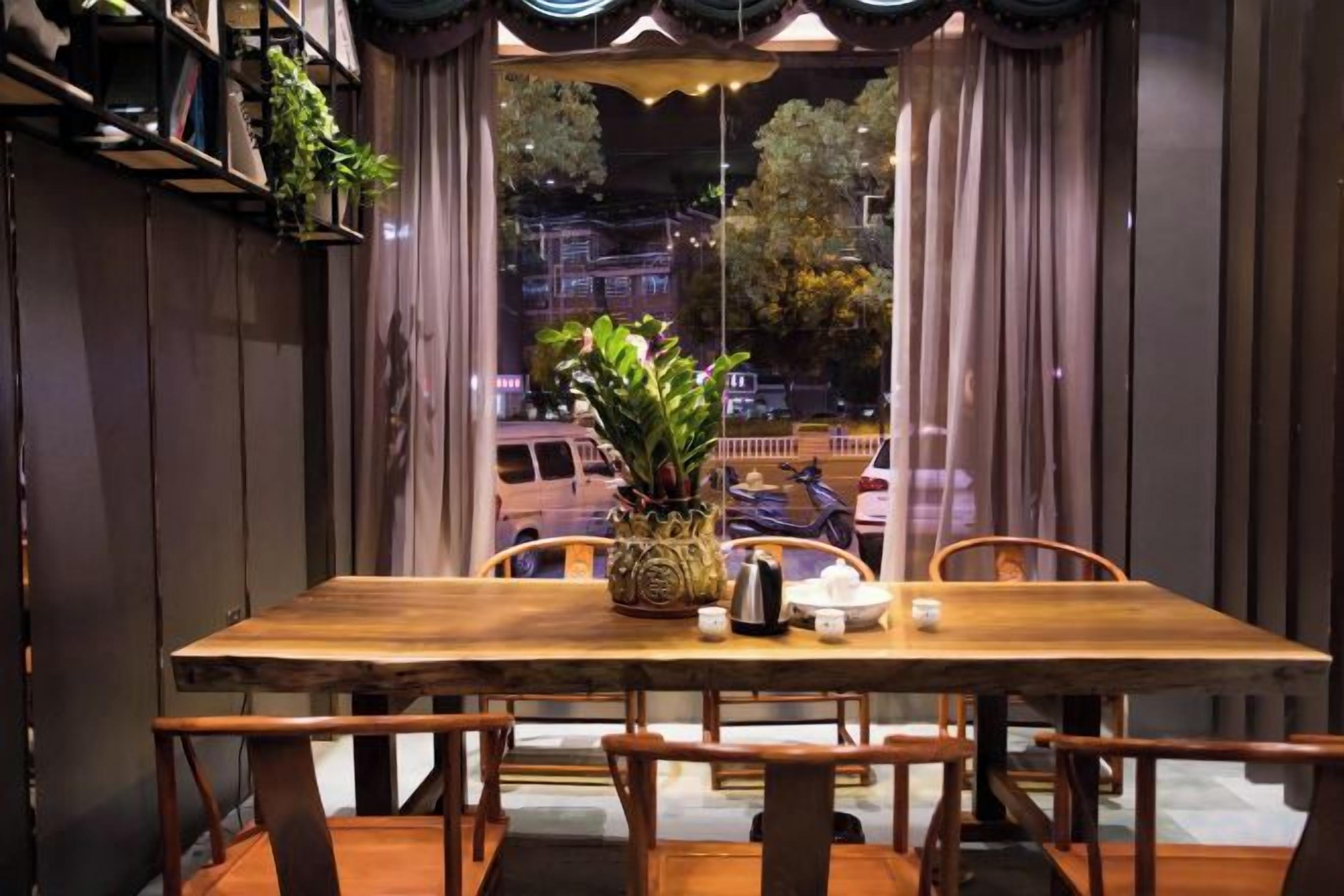Una mesa de comedor de madera con sillas, una planta en maceta y un florero.