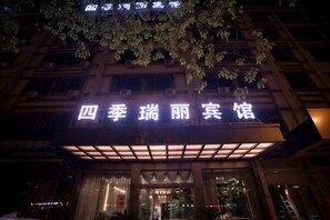A hotel entrance with a sign in Chinese characters, a covered entrance area, and a building facade with windows. - Siji Ruili Hotel (Yiwu)