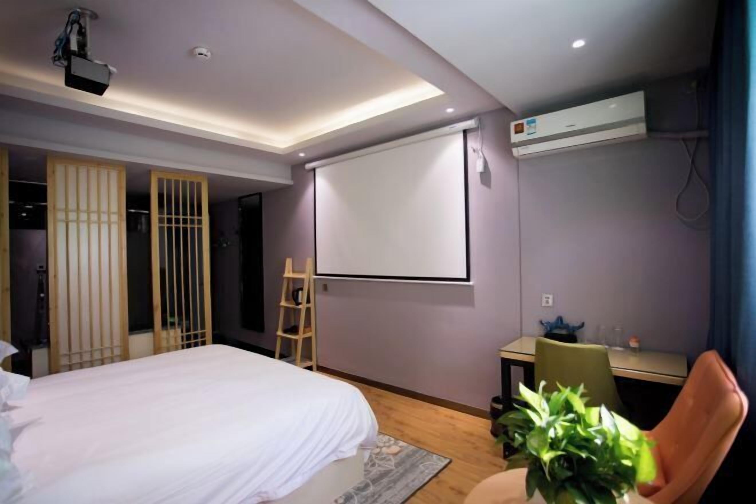 Une chambre d’hôtel moderne équipée d’un lit, d’un bureau, d’un projecteur et d’un appareil de climatisation.