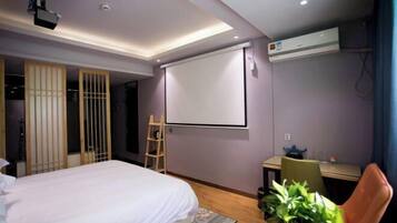 Une chambre d’hôtel moderne équipée d’un lit, d’un bureau, d’un projecteur et d’un appareil de climatisation.