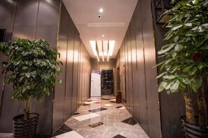 A hallway with a checkered floor, potted plants, and a door at the end. - Siji Ruili Hotel (Yiwu)