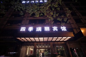 A hotel entrance with a sign in Chinese characters, a covered entrance area, and a tree above. - Siji Ruili Hotel (Yiwu)