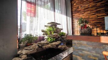 A reception area with a stone water feature, potted plants, and a wooden wall.