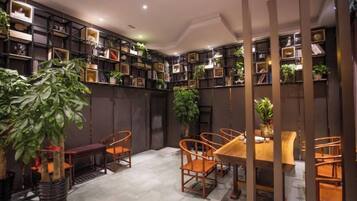 A room with a dining table, chairs, and shelves with books and plants.