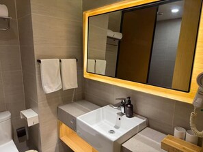 A modern bathroom with a large mirror, a white sink, a towel rack, and a hairdryer. - Ji Hotel (Shanghai)