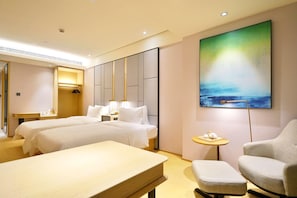 A hotel room with two beds, a desk, a chair, a small table, and a large painting on the wall. - Ji Hotel (Shanghai)