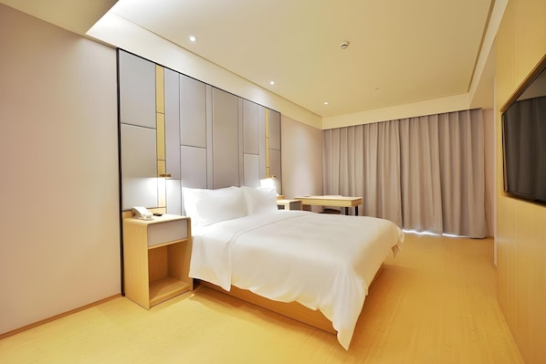 Una habitación de hotel moderna con una cama, mesita de noche, lámpara y vistas al exterior.