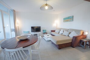 Una sala de estar moderna con un sofá, televisor y mesa de comedor.