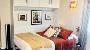 Een slaapkamer met een bed, een kledingkast, een staande lamp en een vloerkleed.