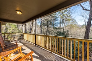 A wooden deck with a railing, benches, and a table.