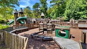 A playground with wooden play structures, including slides and climbing areas, surrounded by trees. - Hilltop Hideaway- Cozy Cabin w/ Fireplace, Private Deck/Yard, Family Friendly! (Cashiers)