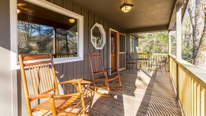 A wooden porch with rocking chairs and a table, overlooking a forested area. - Hilltop Hideaway- Cozy Cabin w/ Fireplace, Private Deck/Yard, Family Friendly! (Cashiers)