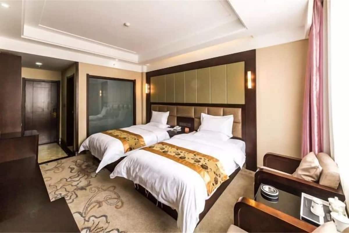 A hotel room with two beds, a desk, and a chair.