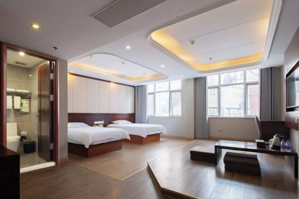 Una habitación de hotel con dos camas, un escritorio, una silla y un televisor.
