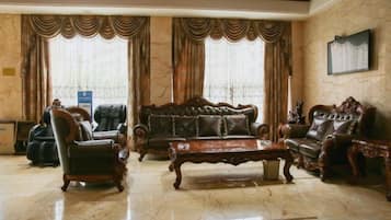 A spacious living room with a large sofa, two armchairs, and a coffee table.