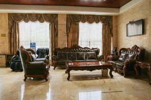 A spacious living room with a large sofa, two armchairs, and a coffee table. - Xianlida Business Hotel (Rui'an)