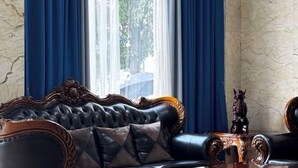 Quarto com sofá de couro preto, cabeceira de madeira decorativa e uma estátua sobre uma mesinha lateral.