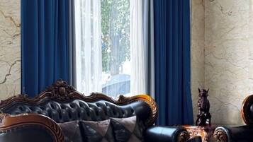 A room with a leather sofa, a decorative table, and a view through a window with blue curtains.