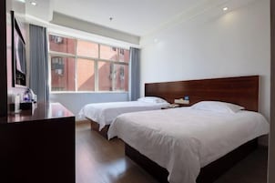 Una habitación de hotel con dos camas, un escritorio y una ventana con vistas a edificios.