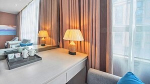 A hotel room with a large window, a desk with a tray of amenities, and a sofa. - Laiyue Hotel (Huidong)