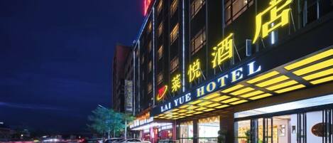 Un hotel con un letrero llamativo, una entrada pavimentada y una fachada bien iluminada.