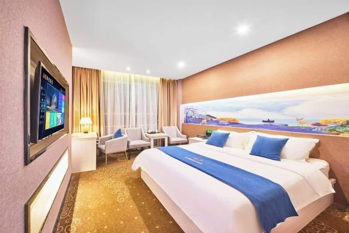 A hotel room with a large bed, a desk, a chair, a TV, and a painting on the wall.
