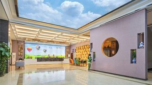 A spacious lobby with a high ceiling, a large digital screen displaying a landscape, and a reception desk. - Laiyue Hotel (Huidong)