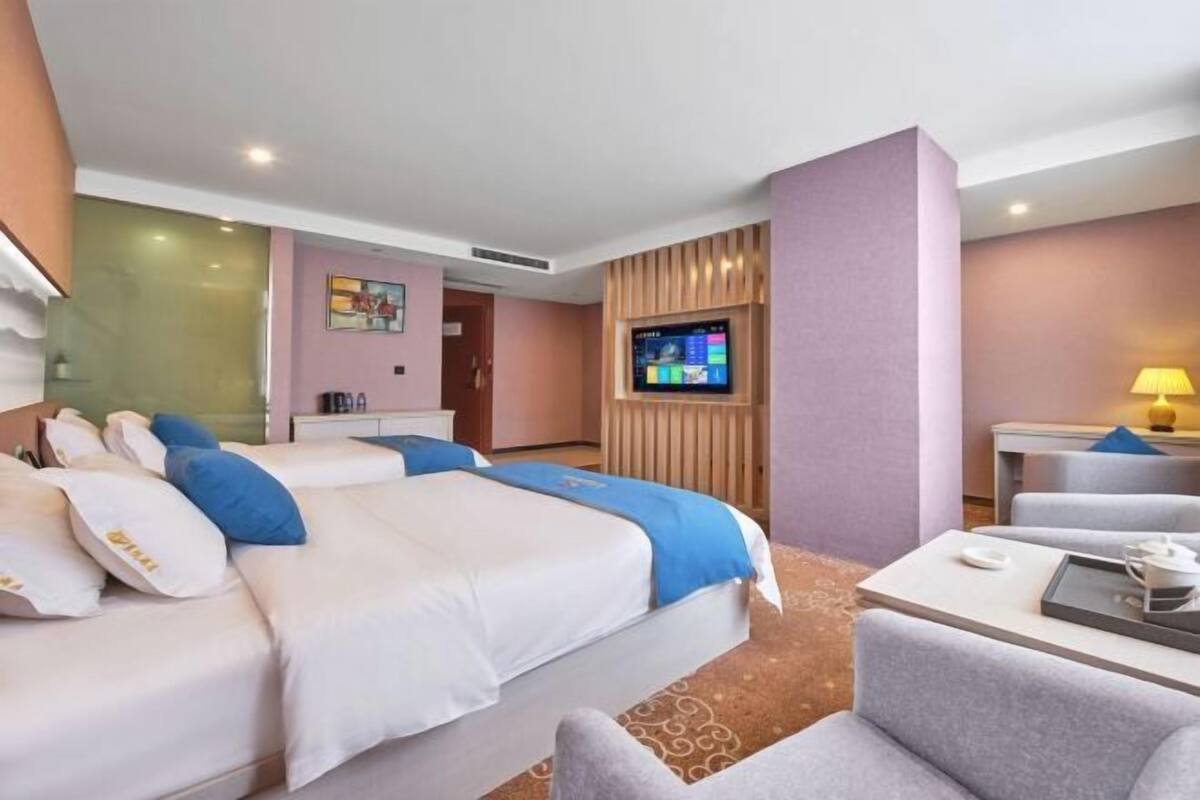 A hotel room with two beds, a TV, a desk, and a chair.