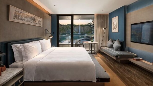 A hotel room with a bed, a seating area, a TV, and a balcony with a view. - Laiyue Hotel (Huidong)