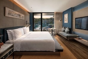 Een hotelkamer met een bed, een zithoek, een televisie en een balkon met uitzicht.