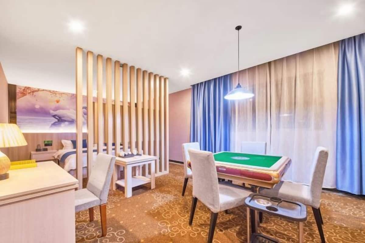 A hotel room with a pool table, a desk, a chair, and a bed.