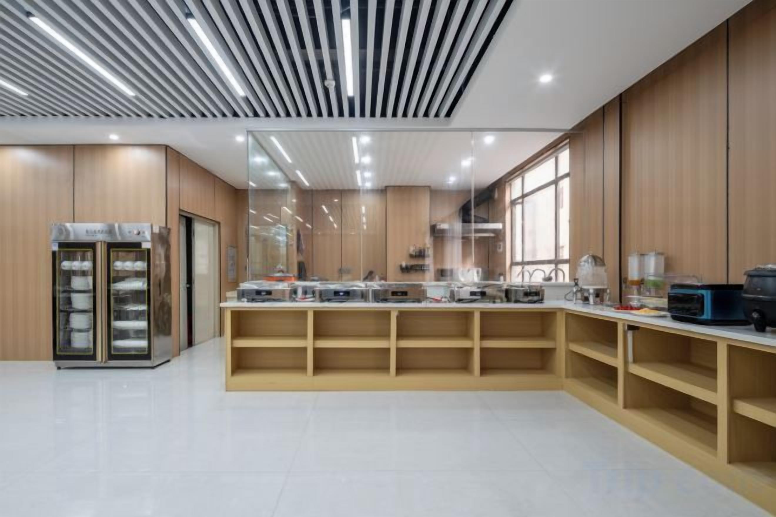 A modern kitchen with built-in appliances, wooden cabinets, and a large window providing natural light.
