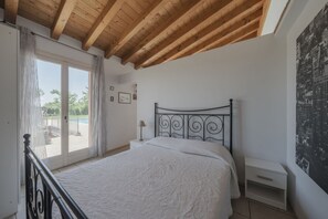 A bedroom with a bed, a nightstand, a lamp, and a view of the outdoors. - La Casina Apartment - with garden and pool (Pozzolengo)
