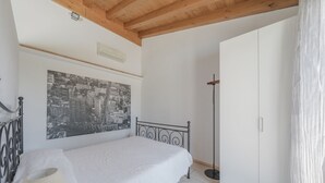 Un dormitorio con cama, armario, un cuadro de paisaje urbano y una lámpara de pie.