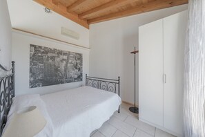 Un dormitorio con cama, armario, un cuadro de paisaje urbano y una lámpara de pie.