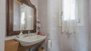 Un baño con tocador de madera, lavabo blanco y un espejo grande.