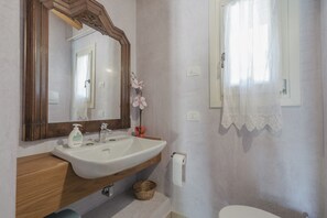 Un baño con tocador de madera, lavabo blanco y un espejo grande.