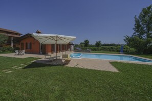 A residential property with a swimming pool, outdoor seating area, and a covered patio. - La Casina Apartment - with garden and pool (Pozzolengo)