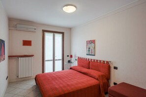 A bedroom with a bed, a radiator, a window, and a door.