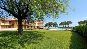 Ein Innenhof mit einem großen Baum, einem Schwimmbecken und einem Gebäude mit Balkonen.