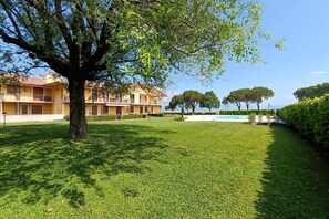 Un cortile con un grande albero, una piscina e un edificio con balconi.
