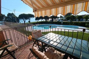 Area piscina con tavolo e sedie in vetro, zona relax coperta e vista sul mare.