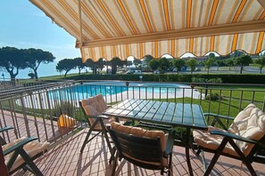 Una terrazza con piscina, arredi da esterno e vista sul mare.