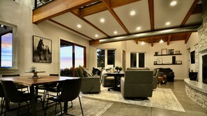 Un vaste espace de vie doté d’un haut plafond, d’une cheminée et d’un coin repas avec une table et des chaises.