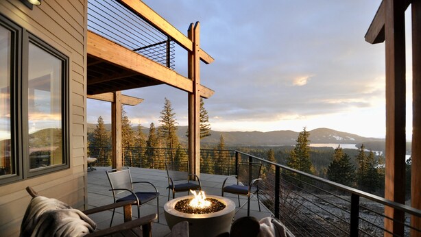 Un balcon doté d’un foyer extérieur, de chaises et offrant une vue sur les montagnes et les arbres.